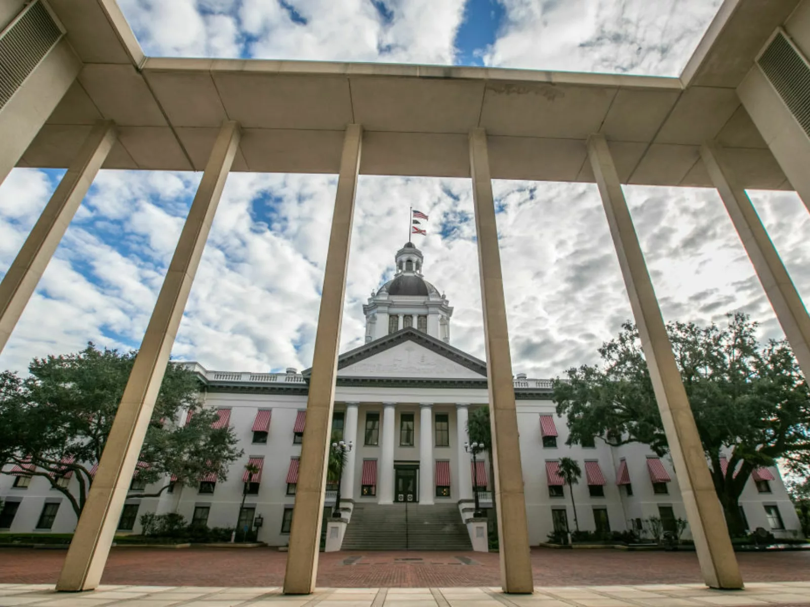Old state capitol building is seen through bars and sits against cloudy sky.