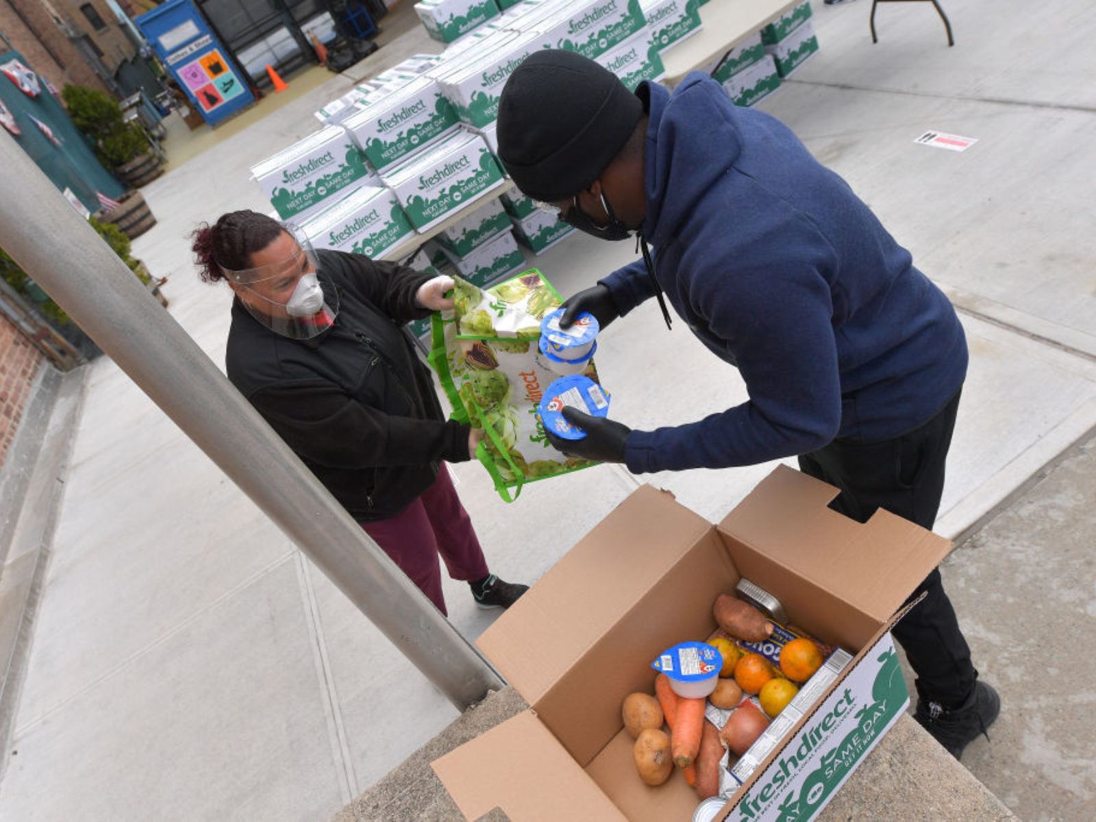 A man hands another man food for distribution.