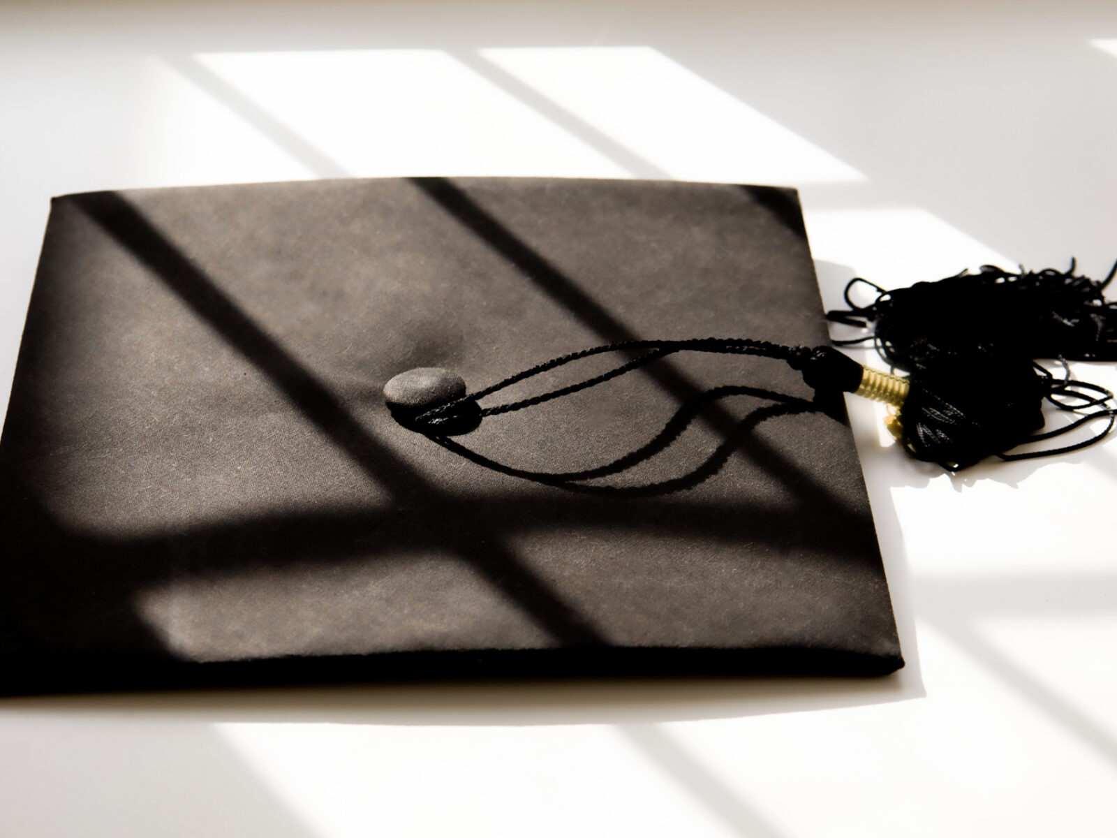 Single black graduate cap on white background with shadow detail.