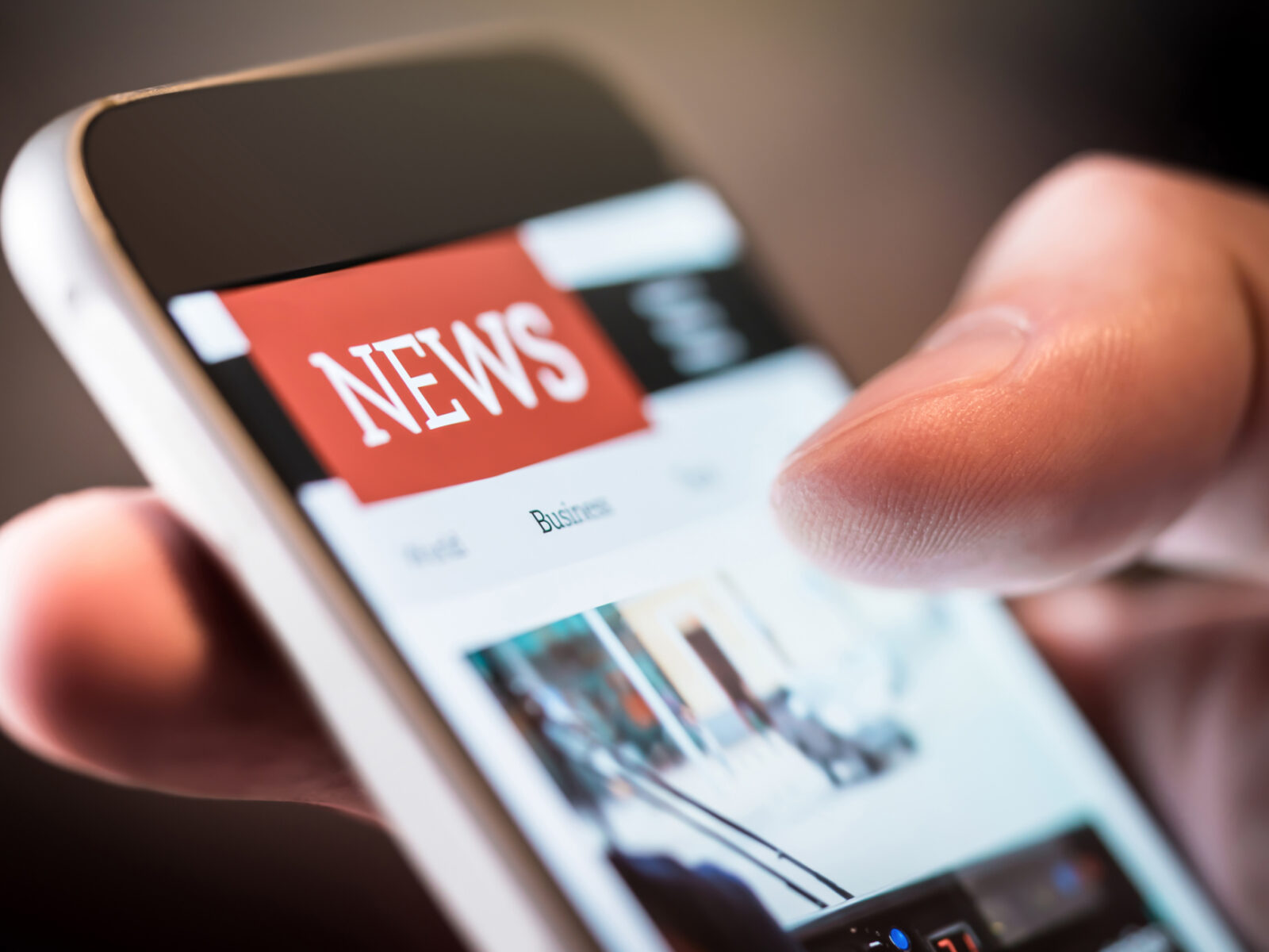 Close up image of smartphone in person's hand and the screen says news.