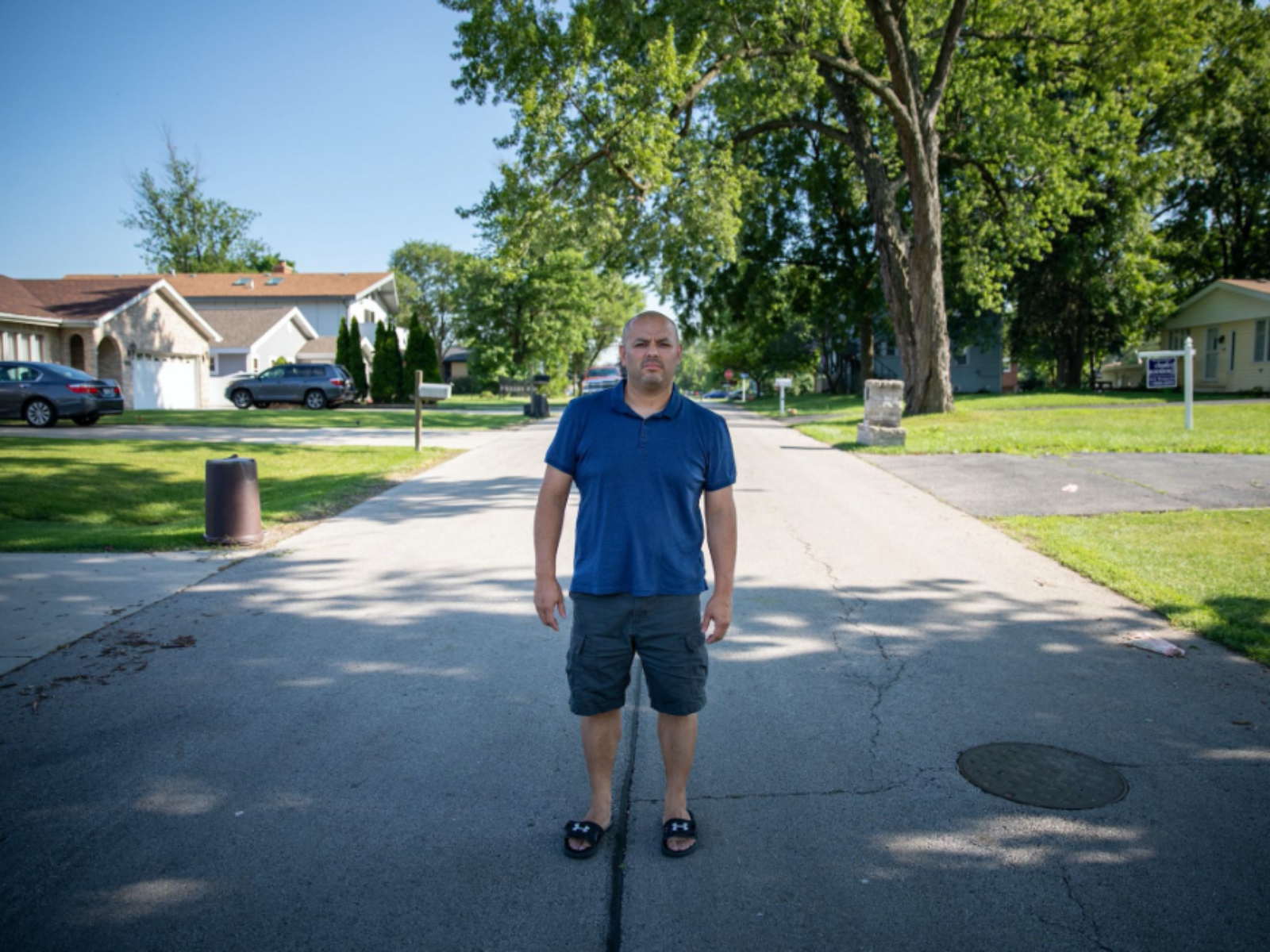 Story subject Jamie Murillo standing in middle of residential street with houses on either side of him.